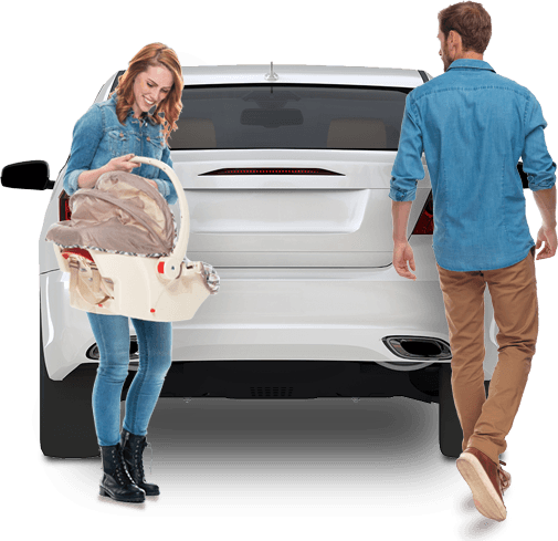 A mother with a baby carrier standing behind a vehicle while the father steps around the vehicle to get something in the car